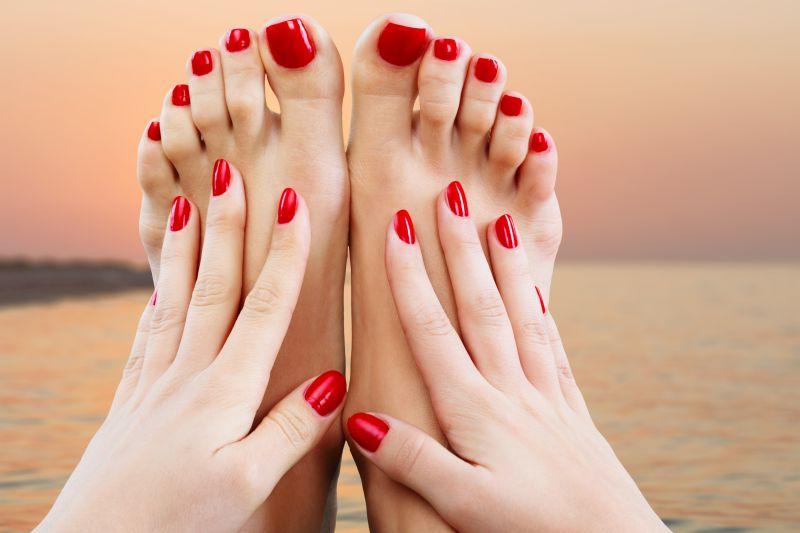 涂着漂亮红色指甲油的女人的双手和双脚