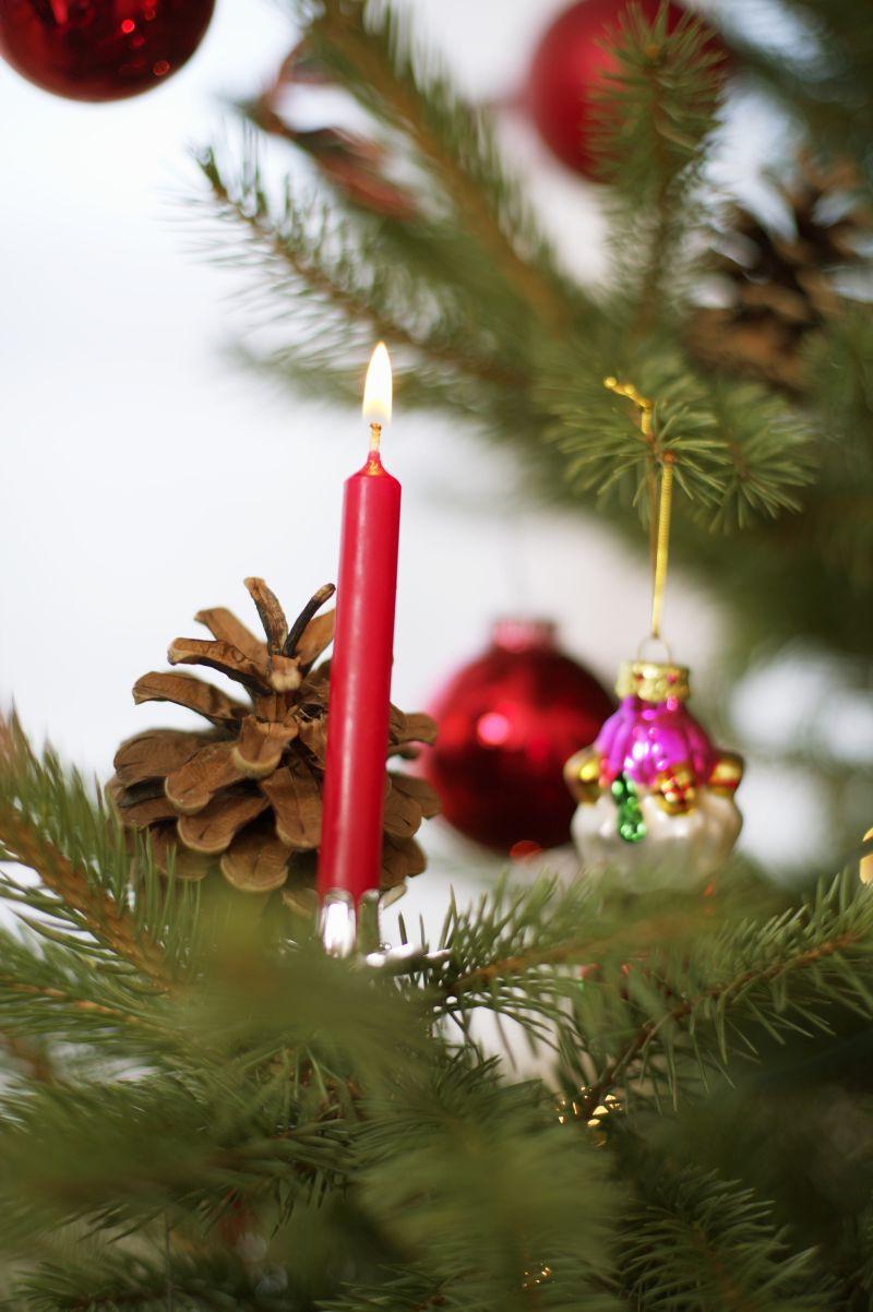 圣诞树上挂着的装饰品和一根点燃的红蜡烛