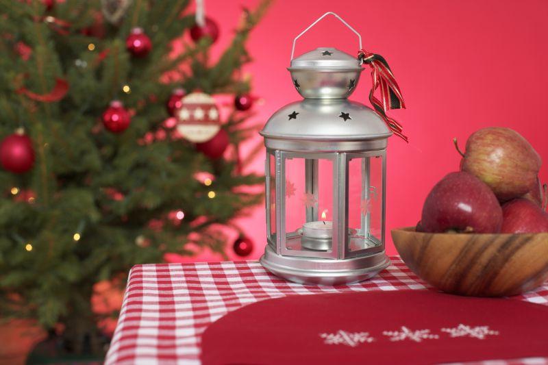 圣诞树边桌子上的油灯和盘子里的苹果