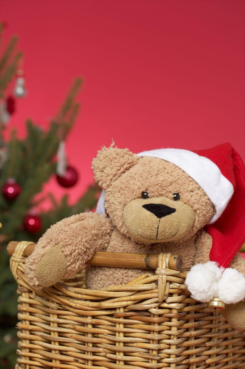 圣诞树边的竹篮里有一只带着圣诞帽的可爱小熊