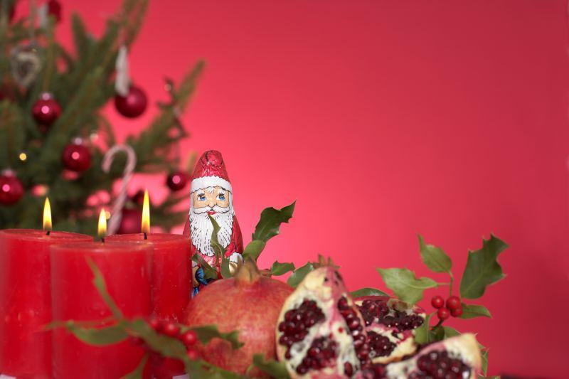 圣诞树边桌子上的圣诞老人和蜡烛和石榴还有野生浆果