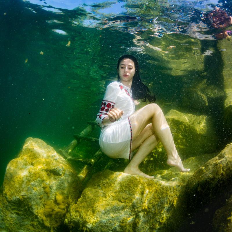 待在水下楼梯旁的穿着乌克兰刺绣服饰的年轻优雅的女子