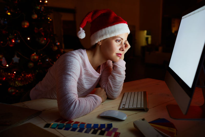 用手托着脸看着电脑屏幕的圣诞女孩