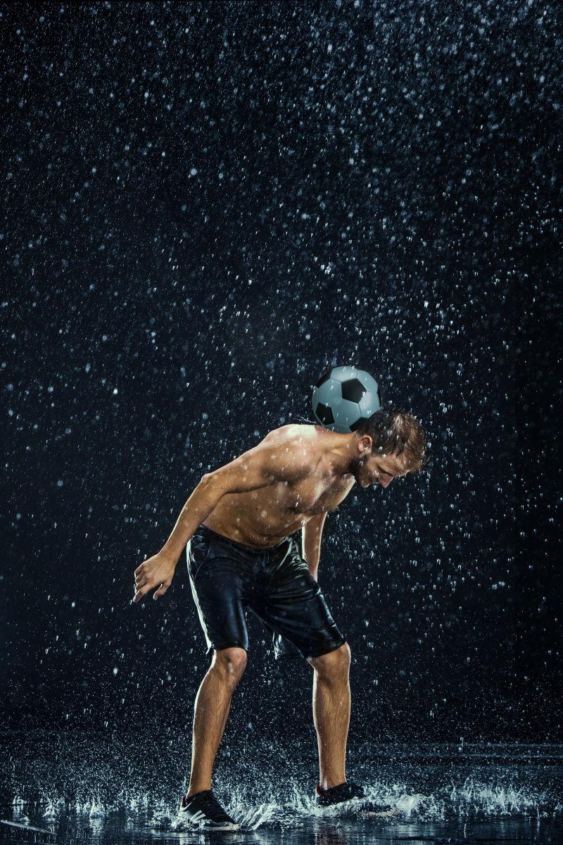 半裸的足球运动员与周围的水滴在黑色背景下