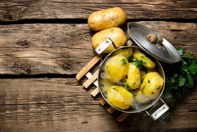 铁锅里的蒸土豆和桌子上的生土豆