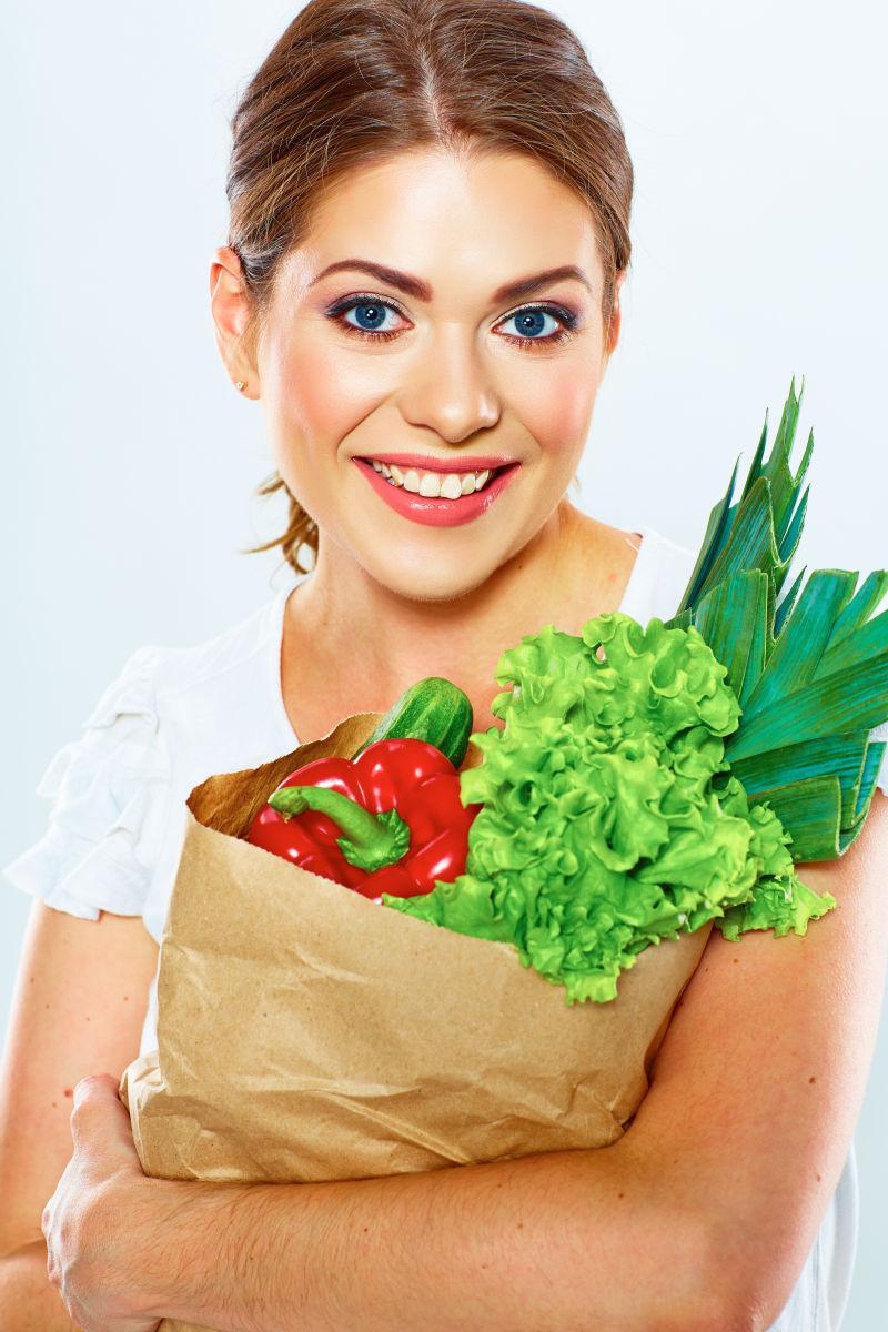 美女微笑的抱着蔬菜
