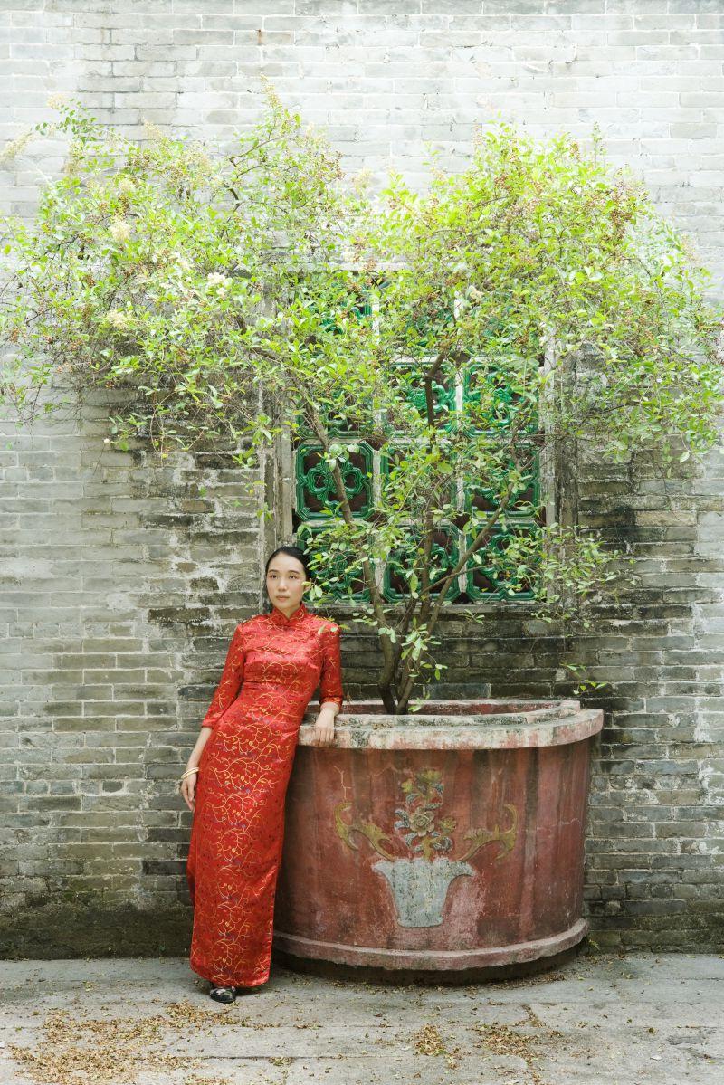 穿着红色旗袍站在院子里的东方美女