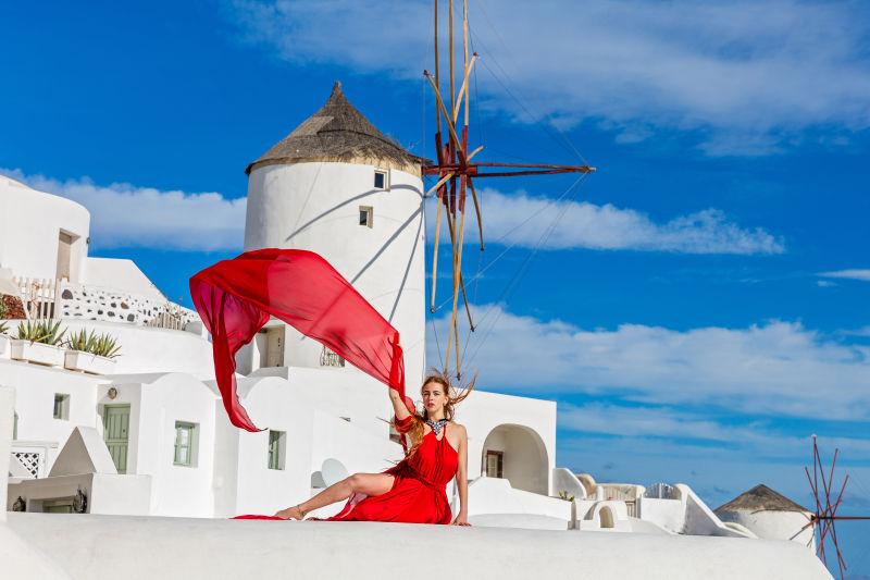 圣托里尼建筑背景下穿的红裙礼服美女