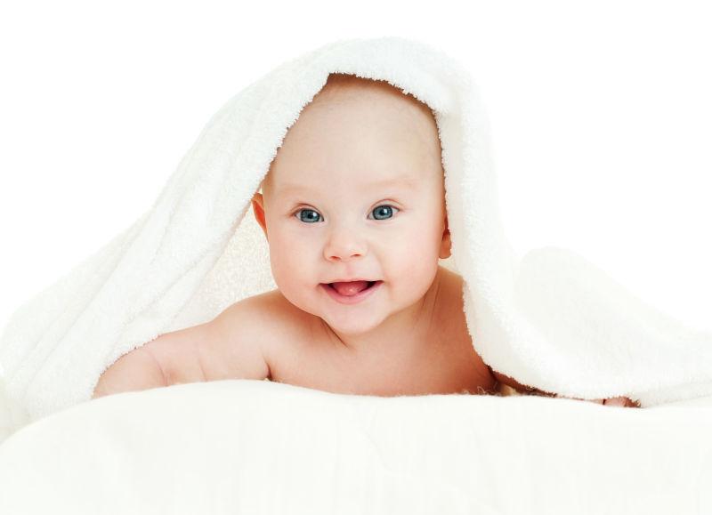白色毛巾下趴着的可爱婴儿