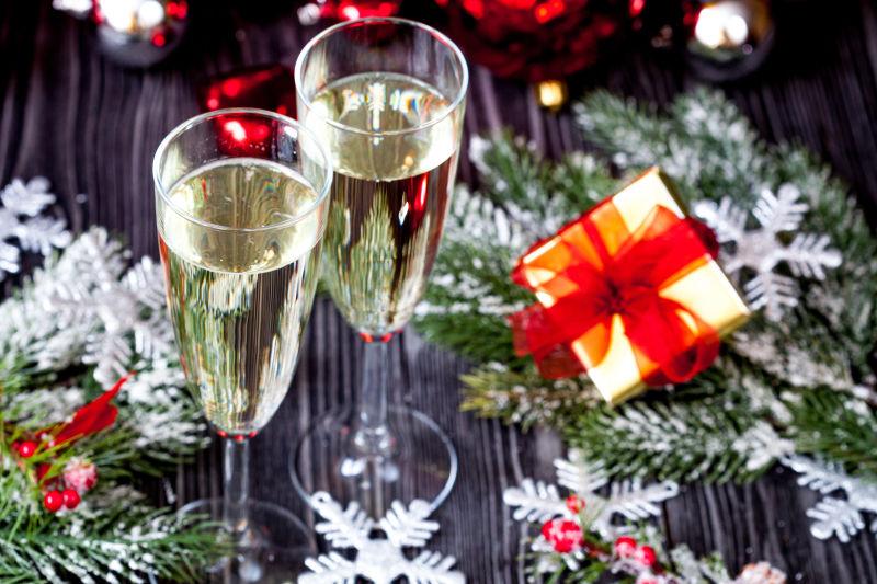 木桌上的圣诞饰品和两杯装满香槟的高脚杯