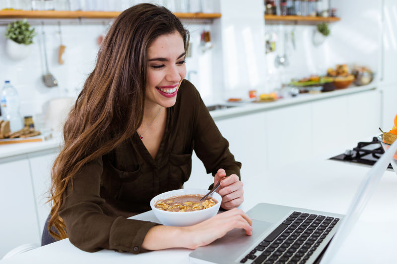 女人在厨房吃早饭玩笔记本电脑