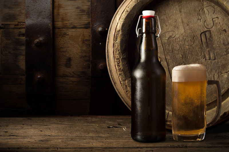 木制背景上的一瓶啤酒和一杯啤酒