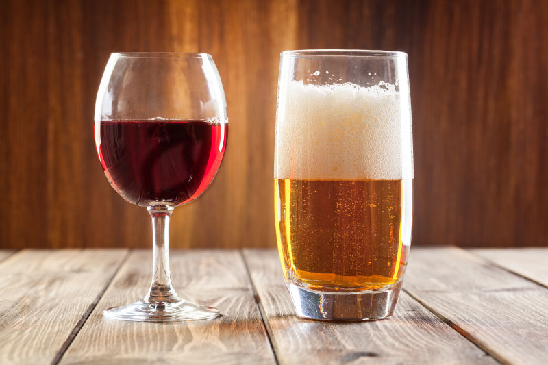 木桌上的一杯红酒和一杯啤酒