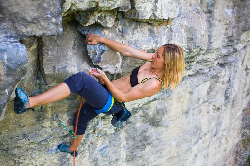 强壮的女孩爬上岩石