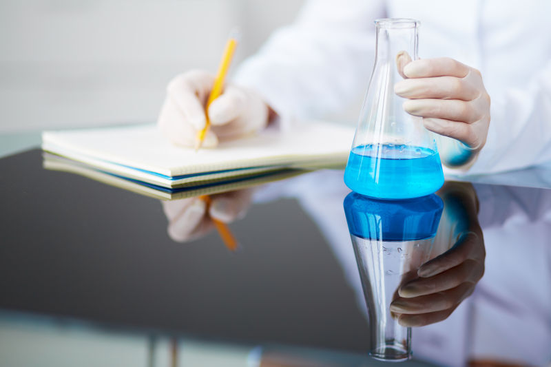 实验室女药师手持蓝液玻璃烧瓶