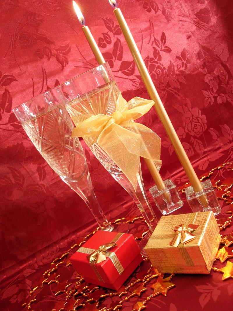 红色背景下的彩色礼品盒和高脚杯里的香槟酒
