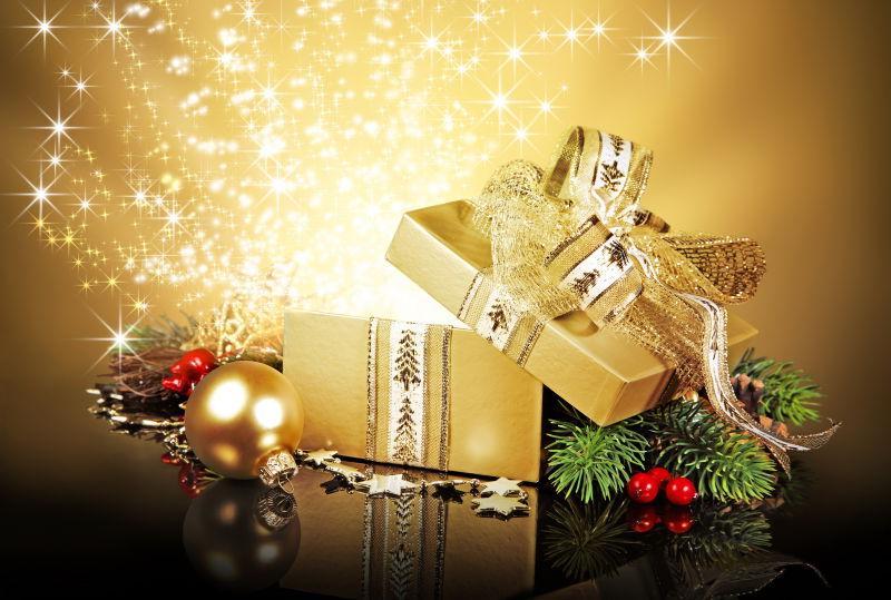 黑色桌上打开发光的金色礼品盒和圣诞节装饰品