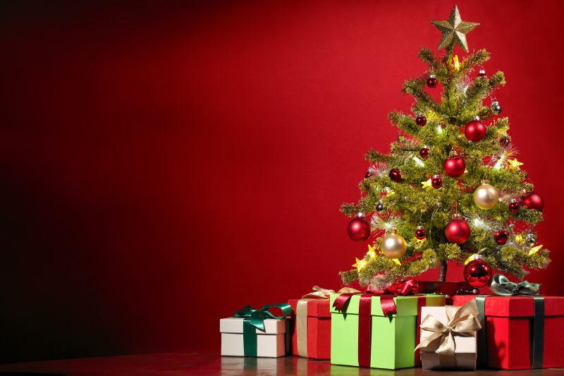 红色背景下的装饰好的圣诞树和礼品盒