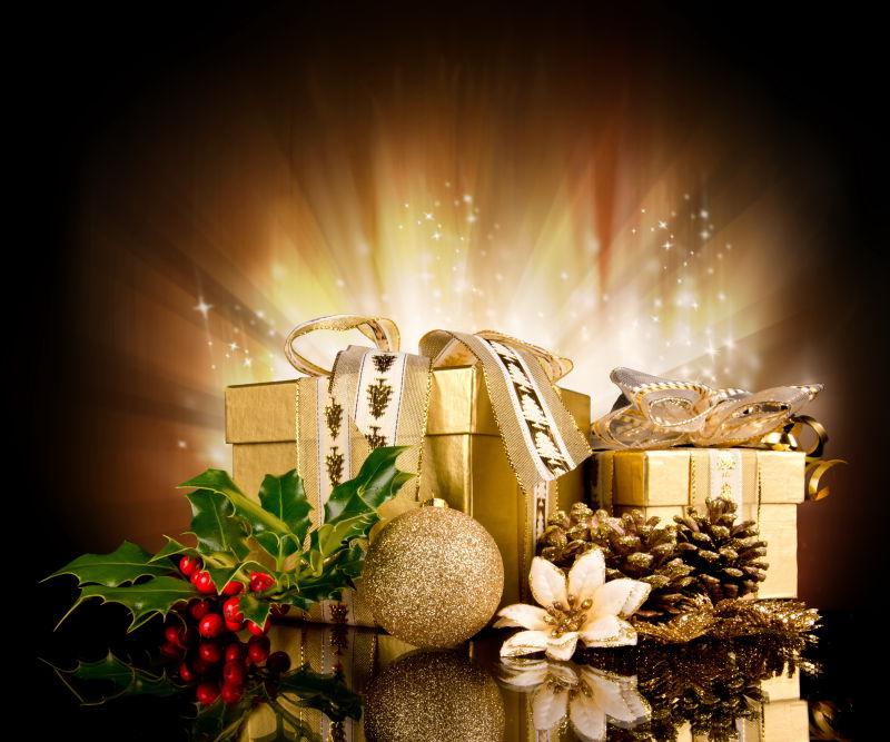 黑色背景下的发光的金色圣诞节礼品盒和装饰品