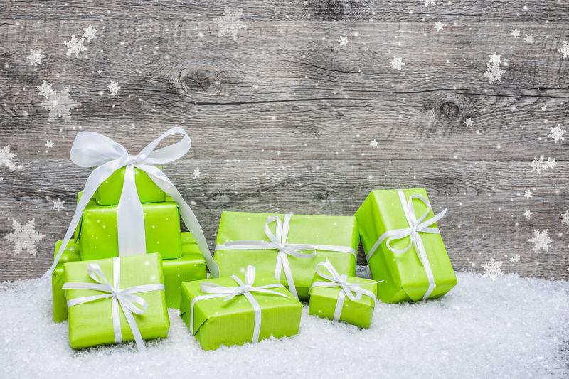 木背景下雪地上的绿色圣诞节礼品盒
