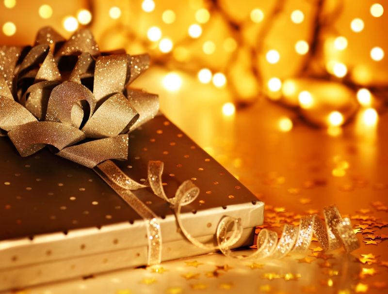 金色的小彩灯背景下的金色圣诞礼品盒