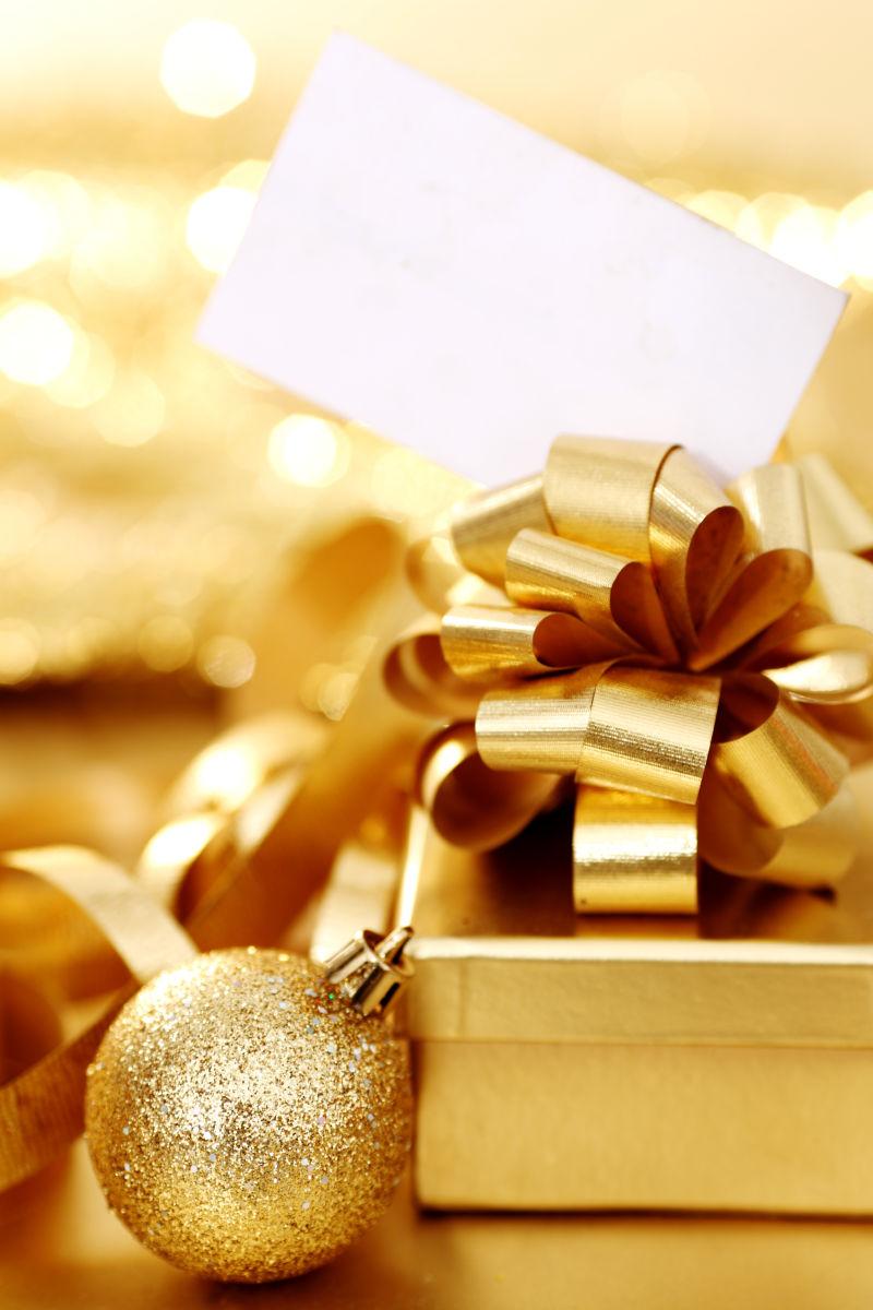 金色背景上的金色的礼品盒装饰品和空白贺卡