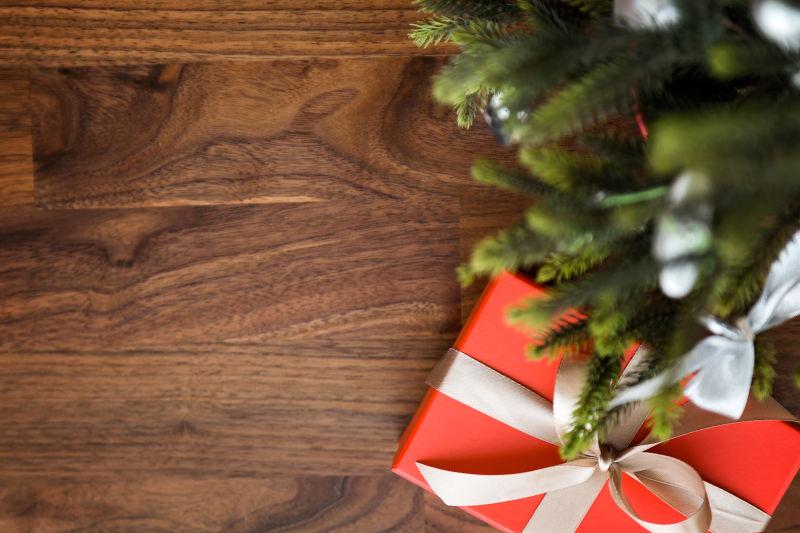 木桌上的圣诞树枝和红色礼品盒