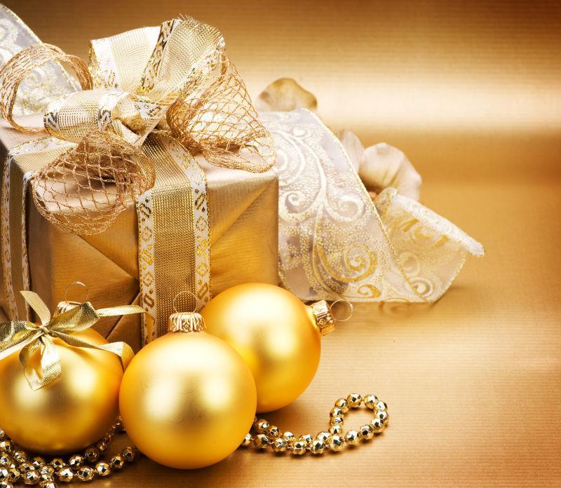 金色背景上的金色的礼品盒和球形装饰品