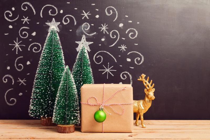 木板上的三颗圣诞树饰品和礼物盒还有可爱的驯鹿饰品