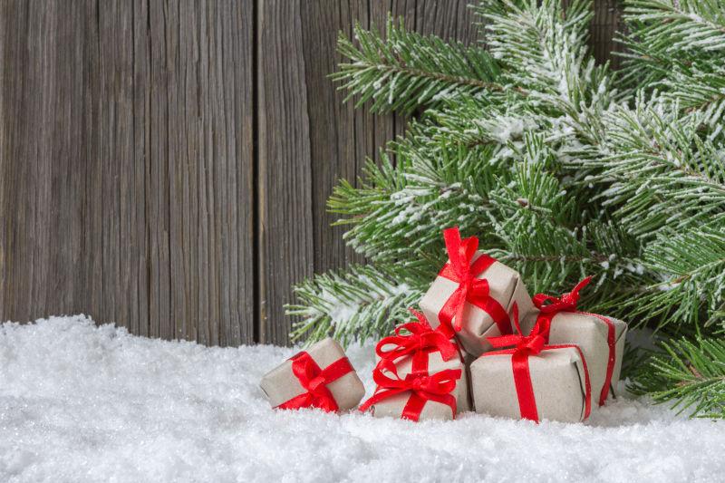 木质背景下雪地上的圣诞树枝和圣诞礼物