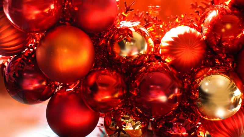 红色圣诞节背景下的金色和红色的球形装饰品