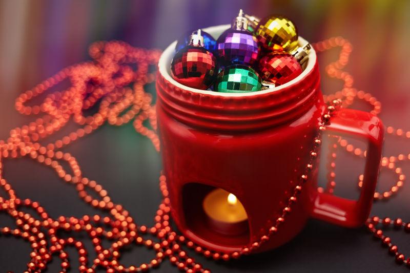 黑色桌上的圣诞节的装满球形装饰品的红色蜡烛灯