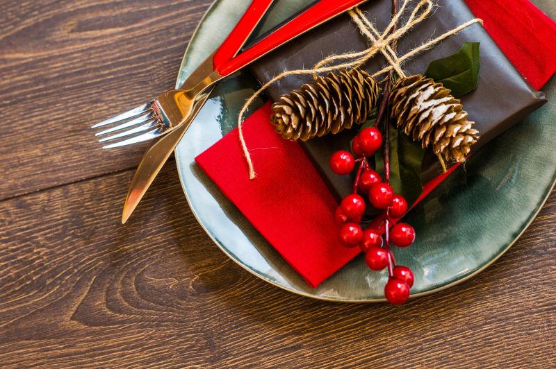 木桌上的有刀叉和松果的圣诞节的餐盘