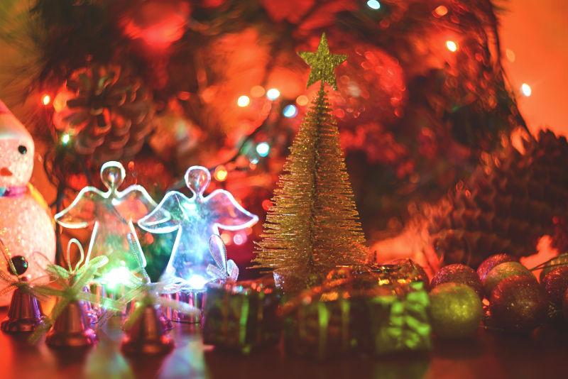 红色灯光下桌上的圣诞树和发光的天使