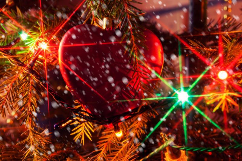暗色背景下的有灯光的圣诞树中间的心形装饰品