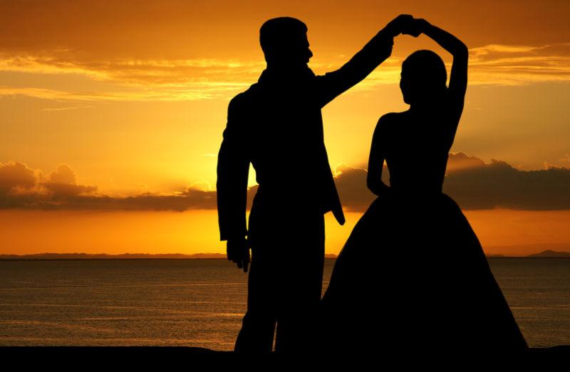 黄昏下海边跳舞的新婚夫妇