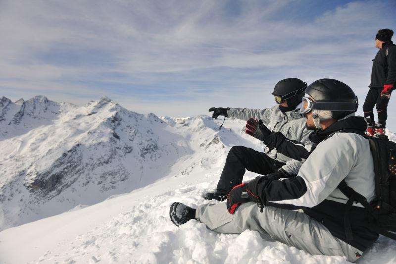 雪山背景上的坐在雪堆上休息的滑雪人