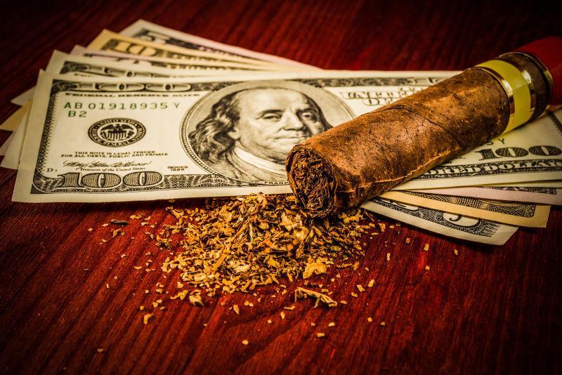 木桌上的美元纸币与雪茄
