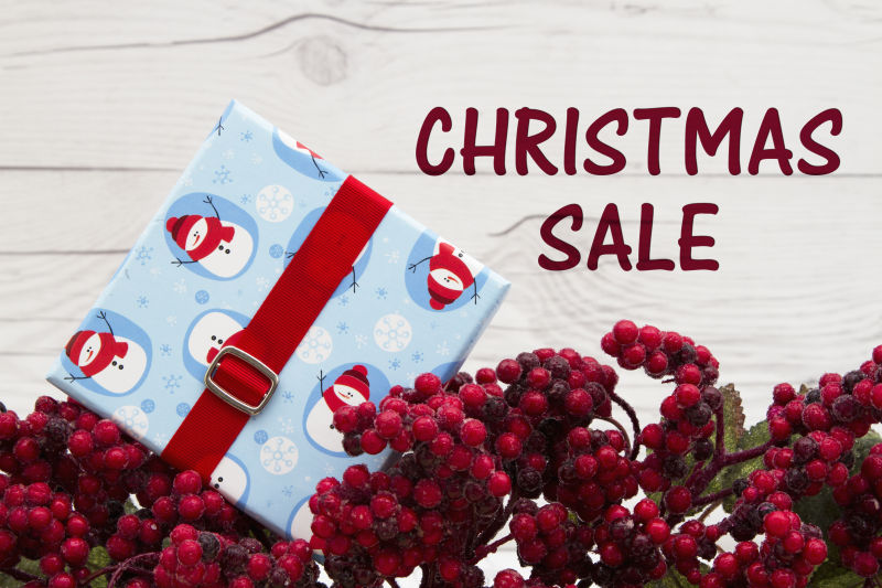 Frost覆盖红色冬青浆果与圣诞礼物风化木材背景与文本圣诞销售