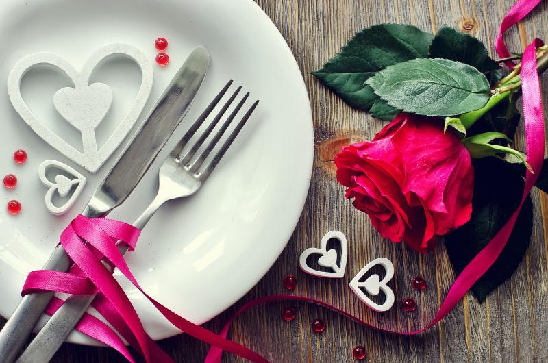 木制背景下的浪漫晚餐餐具和玫瑰