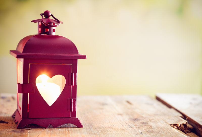 木制背景下的装饰性的红色金属灯笼点缀着情人节的烛光