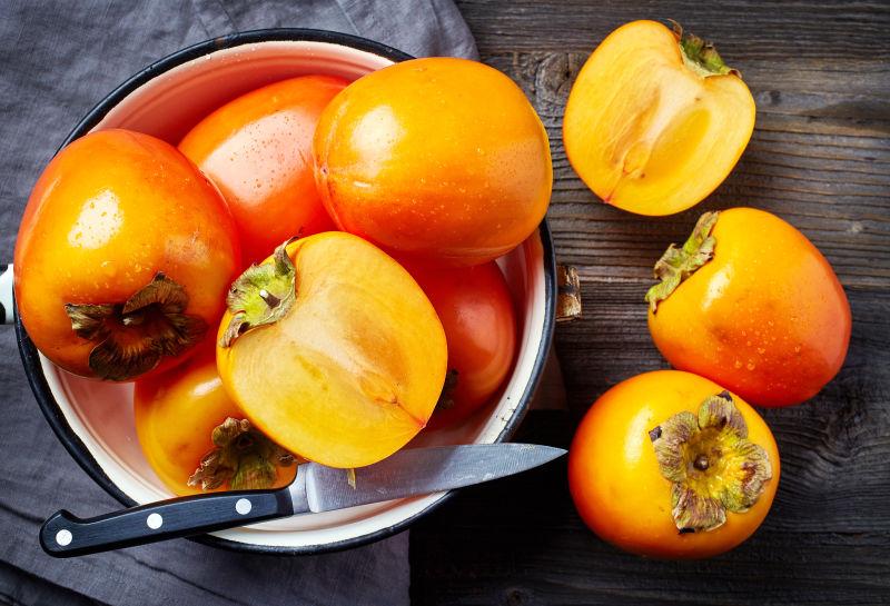 木桌上鲜熟柿子用刀切开