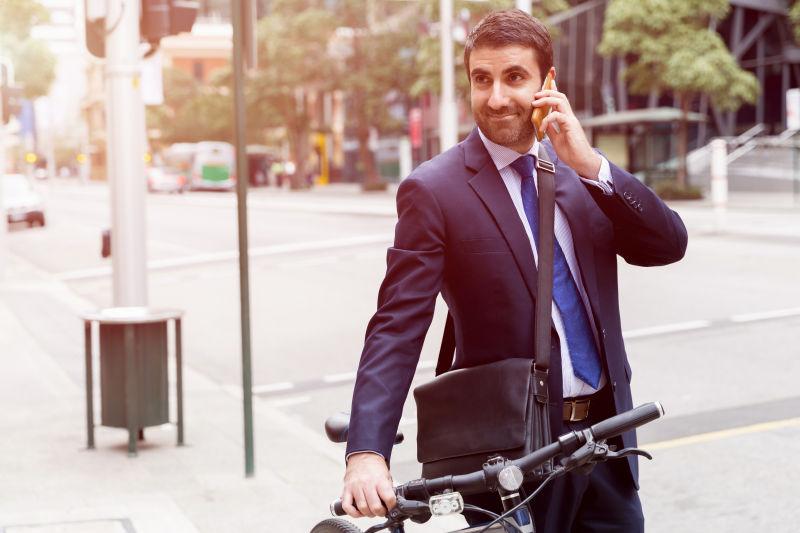 城市街头推着自行车打电话的年轻商人