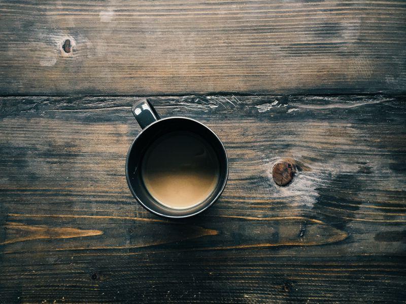 旧木桌上黑色咖啡杯里装着咖啡