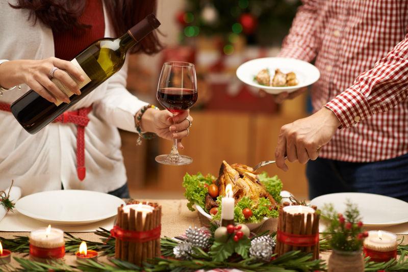 圣诞节晚餐人们吃烤鸡和喝红酒