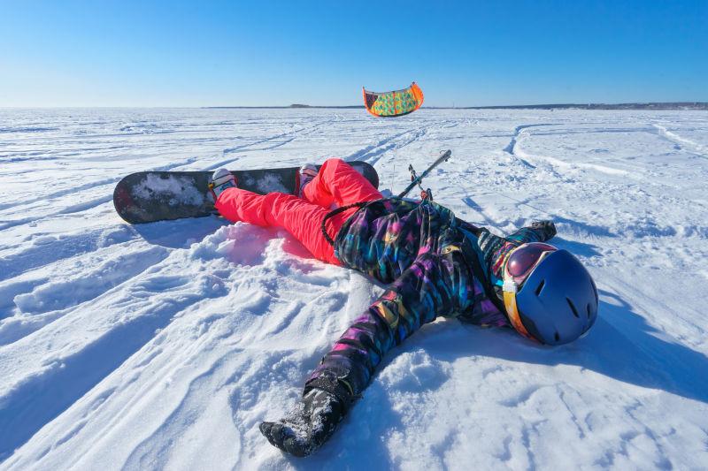 穿着鲜艳衣服的和滑雪板的人躺在雪地上