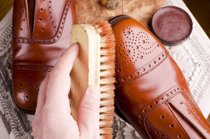 鞋匠指修理鞋子的手和带抛光设备的棕色皮鞋