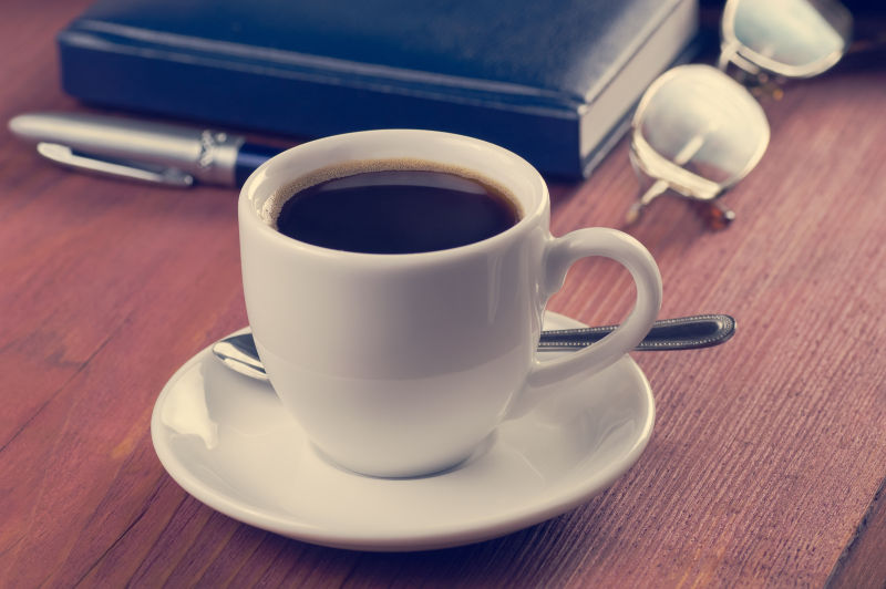 木桌上的日记本和眼镜旁的一杯咖啡