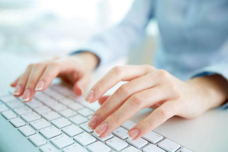 年轻的女人手在电脑键盘上打字