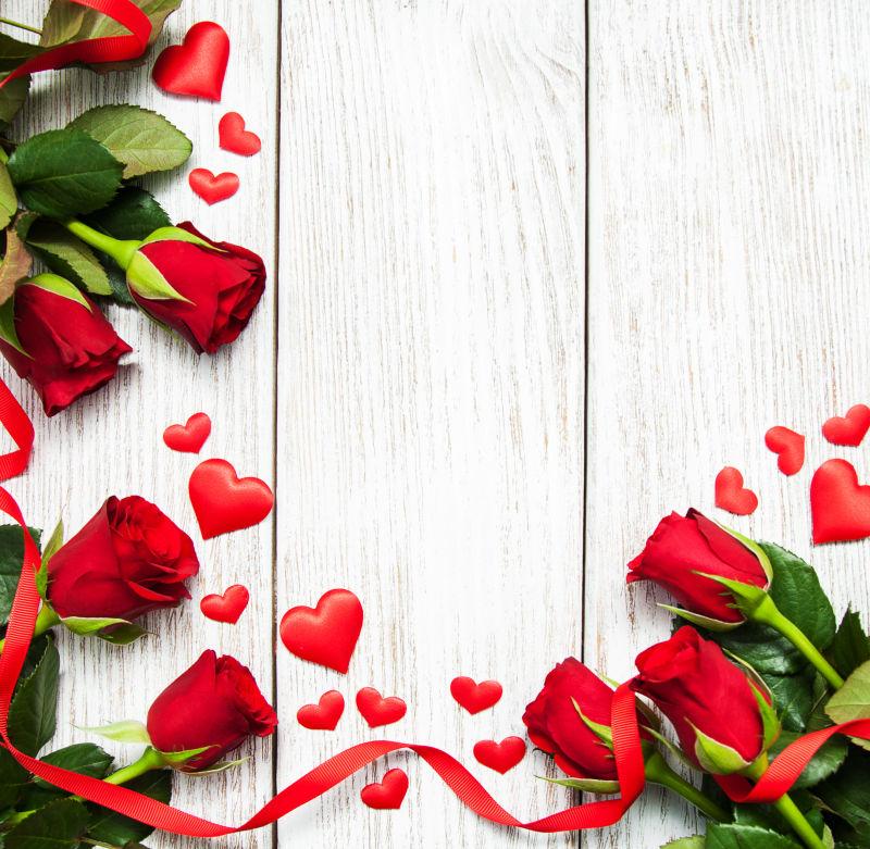 木板上的红色玫瑰花和红色丝带还有爱心装饰品
